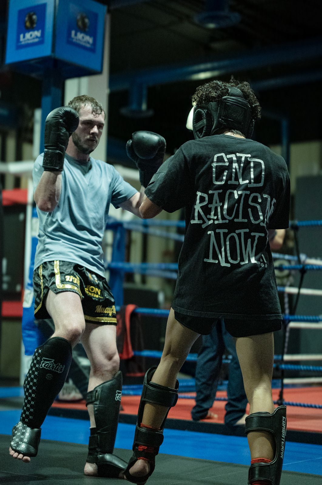 Two fighters sparring in the ring under blue lights