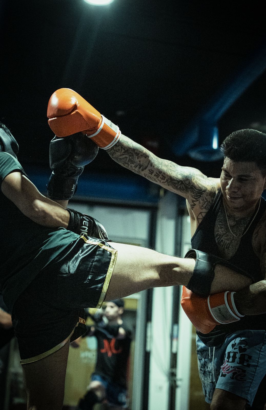 Fighter throwing a kick with orange gloves on the gym mat
